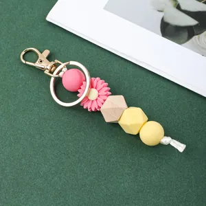 Détail d'un porte-clés en perles de silicone avec une marguerite rose et du bois