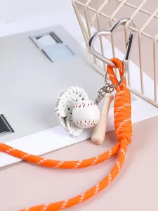Primo piano di portachiavi da baseball retrò con corda intrecciata arancione e accessori mini.