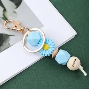 Gros plan sur un porte-clés marguerite en silicone avec perles bleues et perle FAITH gravée