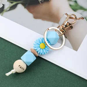 Vue détaillée d'un porte-clés marguerite mignon avec des perles en silicone bleu.