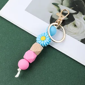 Vue détaillée des perles en silicone colorées et de la marguerite bleue sur le porte-clés doré