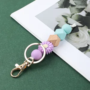 Détail macro montrant des perles en silicone pastel et un charme marguerite sur porte-clés.