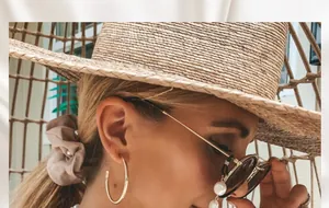 Elegante weiße Perlenbrillenkette mit Goldakzenten an einem weiblichen Modell im Licht