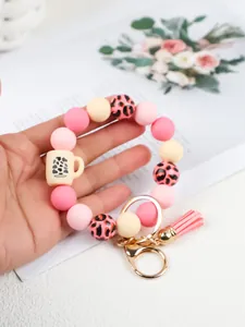 Detail view of silicone bead bracelet keychain with leopard print and pink tassel.