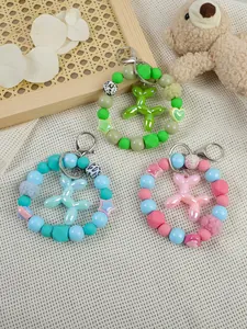 Three colorful balloon dog beaded wristlets and charms on a soft textured background
