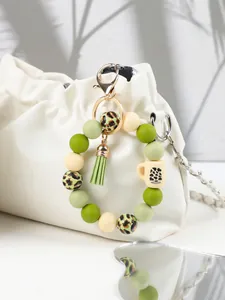 Close-up of leopard silicone bead keychain with green tassel hanging on white bag