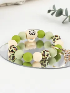 Detail shot of a leopard print silicone bead keychain with a cute cup charm on a mirror