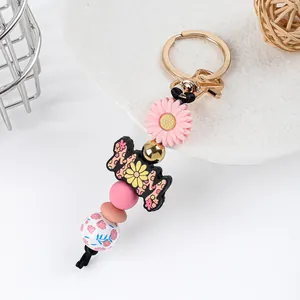 Detailed macro view of a floral silicone bead keychain featuring a pink daisy and MOM charm