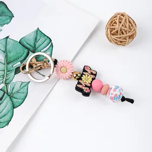 A detailed view of silicone floral beads and daisy charm on a gold-tone keychain.