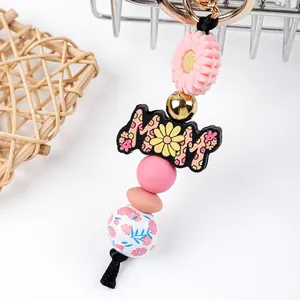 Close-up of silicone floral MOM keychain with pink daisy bead and printed charms