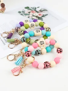 Macro view of leopard print silicone bead wristlet keychains with cup charms and tassels