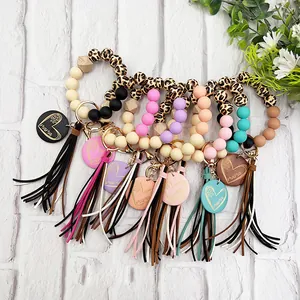 Variety of leopard wood bead silicone wristlet keychains with colorful tassels and charms.