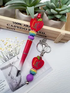 Close-up of TEACH apple silicone beaded pen and matching rainbow rhinestone keychain set