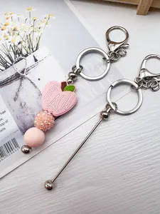Detail view of pink TEACH apple bead and rhinestone ball on a silver keychain stick.