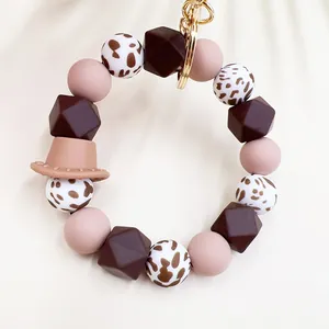 Dettaglio del bracciale in silicone con ciondolo a cappello da cowboy e perle maculate.