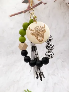 Detail view of western cow print silicone bead keychain with engraved yak wood disc