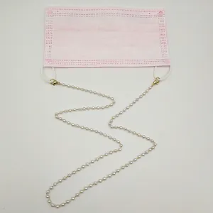 Vue détaillée d'une chaîne de masque en perles blanches fixée sur un masque rose