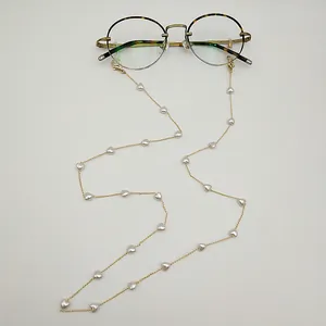 Détail de chaîne à lunettes dorée avec perles blanches en cœur et boucles antidérapantes.