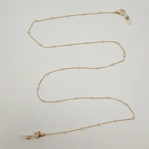 Détail d'une chaîne dorée avec petites perles blanches pour accessoires masques ou lunettes.