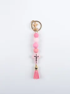 Detail of handmade pink silicone beads and Jesus cross keychain accessory with tassel