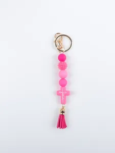 Macro view of pink silicone bead keychain with Jesus cross and tassel charm decoration