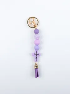 Close-up detail of purple silicone beaded keychain with a Jesus cross and tassel charm