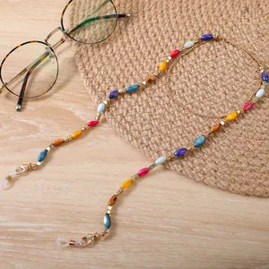 Dettaglio ravvicinato di una catenella per occhiali con perline colorate e distanziatori oro.