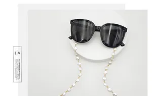 Nahaufnahme der eleganten weißen Perlenbrillenkette mit goldenen Gliedern für Zubehör