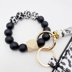 Detalle de cuentas de silicona de leopardo y aros dorados en un elegante llavero de pulsera