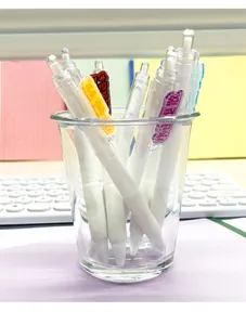 Weiße einziehbare Gelschreiber mit lustigen Comic-Aufklebern in einem Glasbecher aufbewahrt
