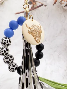 Close-up of Western style highland cow keychain with silicone beads and cow print tassel