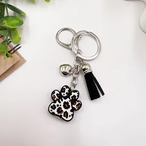 Gros plan sur un porte-clés patte léopard avec breloque cœur et pompon noir
