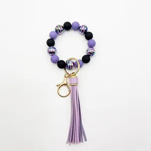 Detailed view of purple zebra stripe beaded bracelet with leather tassel and gold clasp.
