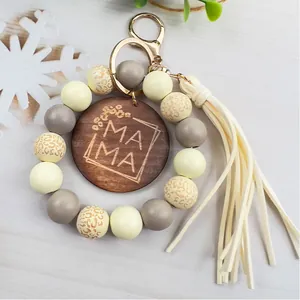 Detalle de llavero de cuentas de madera con disco grabado MAMA y borla beige