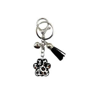 Porte-clés patte léopard en silicone avec pompon noir et breloque cœur sur fond blanc