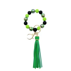 Handmade zebra pattern beaded bracelet keychain with green leather tassel accents