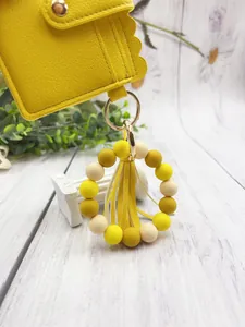 Detail of yellow PU leather card holder with silicone bead ring and tassel keychain.
