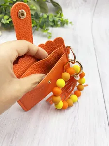 Close-up detail of orange PU leather card holder with colorful silicone bead wristlet