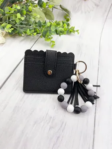 Close-up of black PU leather card holder with silicone bead bracelet and tassel keychain