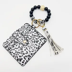 Detalle del tarjetero de leopardo con pulsera de cuentas de silicona y borla.