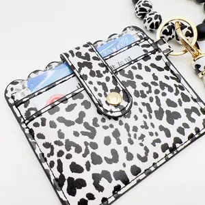 Detalle de tarjetero de leopardo con pulsera de cuentas de silicona y borla suave