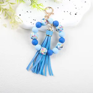 Close-up of blue silicone bead bracelet with floral octagon beads and tassel detail.