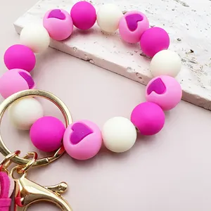 Detailaufnahme des pink-weißen Silikonperlen-Armband-Schlüsselanhängers mit Herzmuster