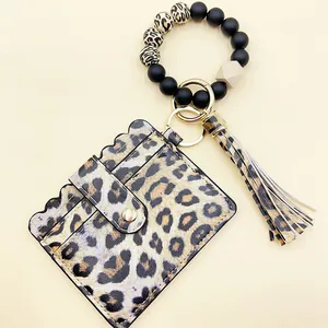 Detalle de tarjetero leopardo con pulsera de cuentas de silicona y borla llavero