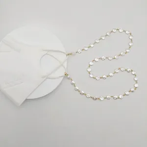 Elegante Perlen-Maskenkette und Brillenhalskette mit Goldgliedern auf weißem Grund