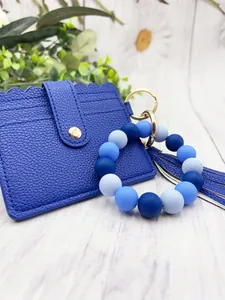 Close-up of blue silicone bead bracelet with PU leather card holder and tassel.