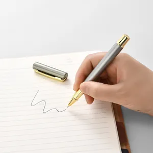Elegant silver metal business ballpoint pen being used by a hand on a notebook