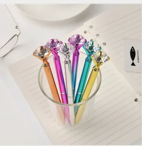 Colorful metallic ballpoint pens with large crystal diamond tops in a glass cup.
