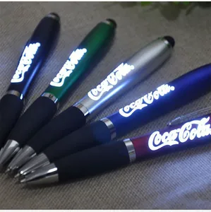 Detailed macro view of multiple glowing LED light-up ballpoint pens with stylus touch tips.