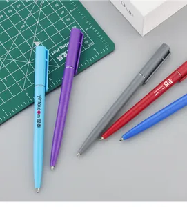 Detail shot of colorful plastic ballpoint pens with custom printed logos on a desk.